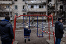 Ο πόλεμος στην Ουκρανία σε μία εικόνα: Ένα παιδί κάθεται σε μία κούνια κοιτάζοντας τα κατεστραμμένα κτίρια