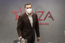 Ο Αλέξης Τσίπρας με μάσκα μπροστά από σήμα του ΣΥΡΙΖΑ