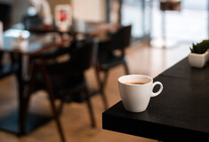 Φλιτζάνι με καφέ σε τραπέζι, μπροστά από θολό φόντο