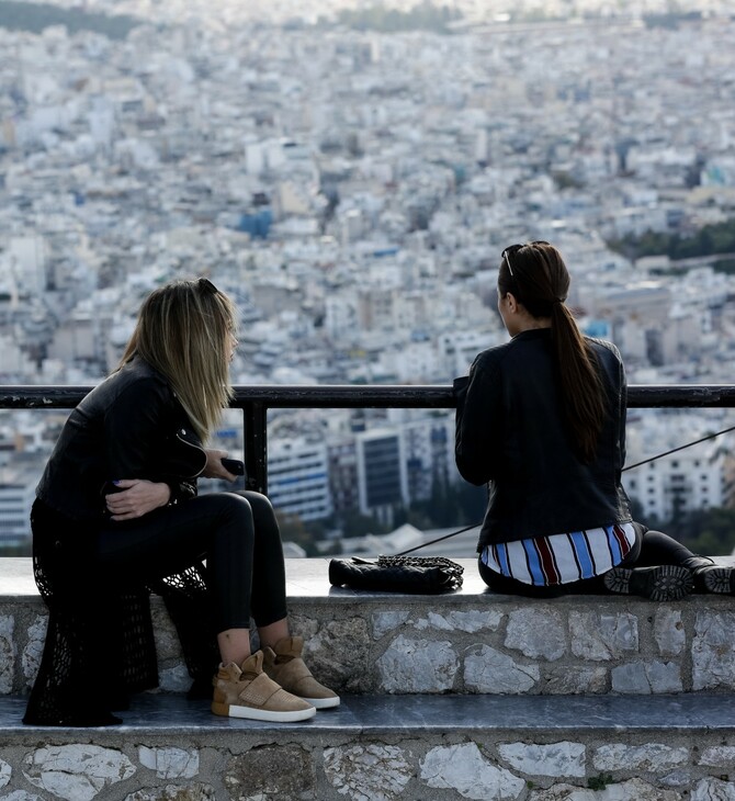 Δύο γυναίκες κάθονται σε πεζούλι