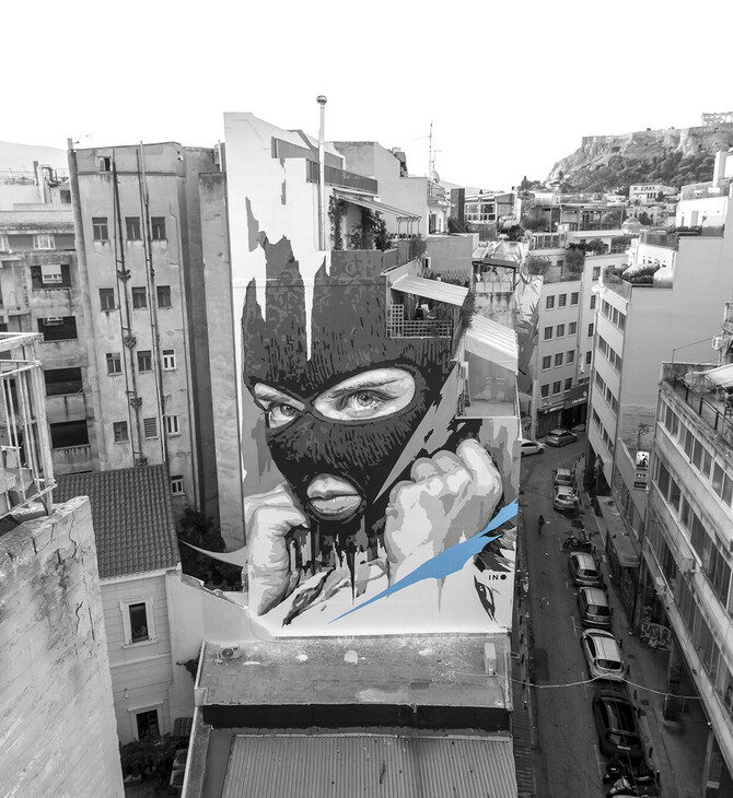 Ο ΙΝΟ ζωγραφίζει στα κτίρια της Αθήνας κρεμασμένος με σχοινιά