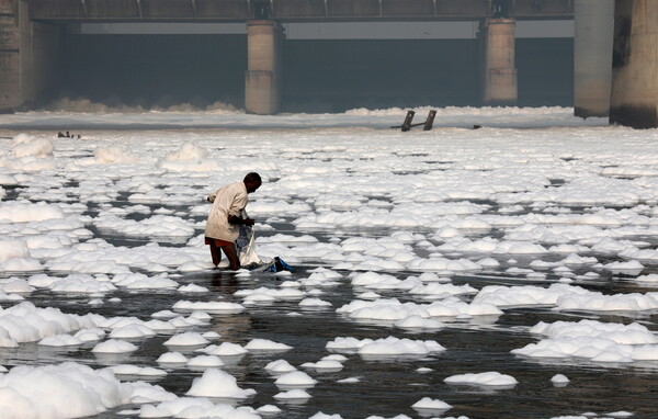 Toxic foam coats sacred river in India as Hindu devotees bathe in its waters