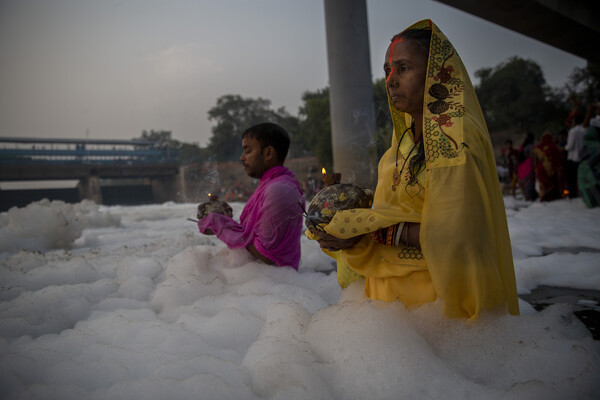Ινδουιστές κάνουν μπάνιο και προσεύχονται στον ιερό ποταμό Yamuna καλυμμένοι με τοξικό αφρό