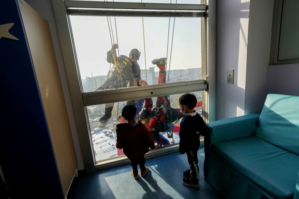 Acrobatic superheroes scale children's hospital to visit young patients