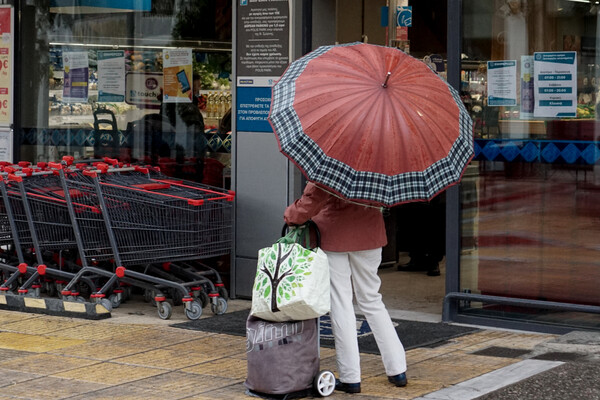 Γυναίκα με ομπρέλα έξω από σουπερμάρκετ