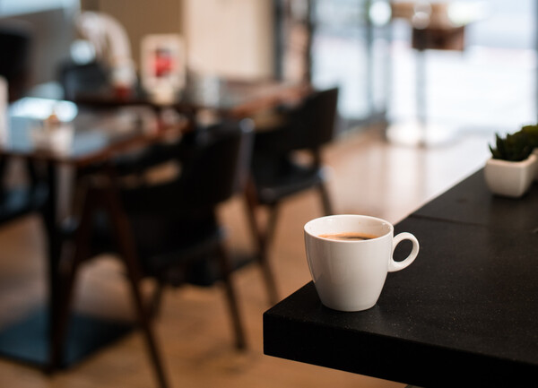 Φλιτζάνι με καφέ σε τραπέζι, μπροστά από θολό φόντο
