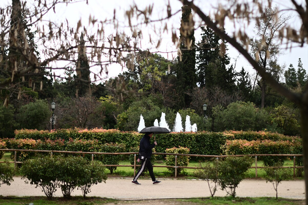 Άνδρας με ομπρέλα μπροστά από συντριβάνι