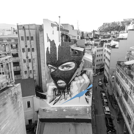 Ο ΙΝΟ ζωγραφίζει στα κτίρια της Αθήνας κρεμασμένος με σχοινιά
