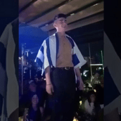 Eurovision 2023: Ο Βίκτωρ Βερνίκος όρθιος πάνω σε τραπέζι, τραγουδά με την ελληνική σημαία