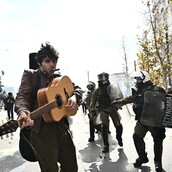 Πορεία για τα Τέμπη στην Αθήνα: Μουσικός με την κιθάρα του δίπλα από τα ΜΑΤ την ώρα των επεισοδίων