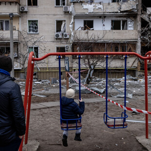 Ο πόλεμος στην Ουκρανία σε μία εικόνα: Ένα παιδί κάθεται σε μία κούνια κοιτάζοντας τα κατεστραμμένα κτίρια